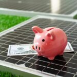 Solar panel model and piggy bank close up, energy savings concept